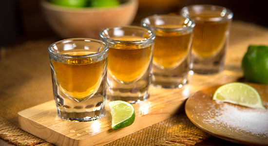 Four glasses of Anejo sipping tequilas with limes