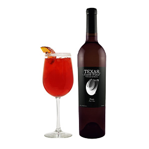 A bottle of Texas South Wind Plum Wine next to a red cocktail in a wine glass