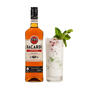 A bottle of Bacardi rum next to a white cocktail in a tall glass